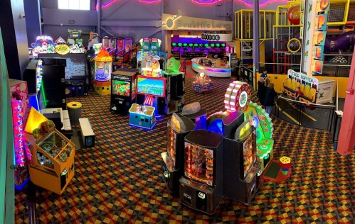 A vibrant arcade filled with colorful games, bright lights, and a checkered floor, inviting fun and entertainment.