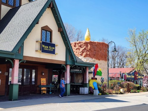 A charming candle outlet with a large decorative candle sculpture outside, featuring colorful designs and a welcoming entrance.