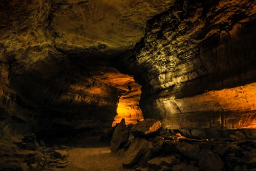 A dimly lit cave interior with rocky formations and an illuminated column, creating a mysterious atmosphere.