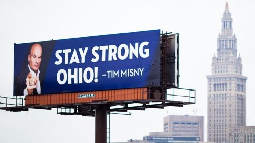 Billboard reading "STAY STRONG OHIO! - TIM MISNY" with a city skyline in the background.