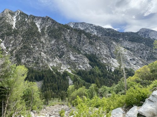 A scenic view of rugged mountains covered in greenery, with a partly cloudy sky above.