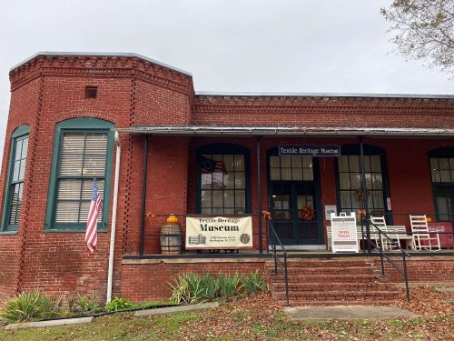 Exterior of the Textile Heritage Museum, featuring red brick walls, large windows, and a welcoming entrance.
