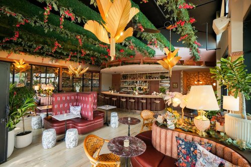 A stylish restaurant interior featuring lush greenery, elegant lighting, and cozy seating arrangements.