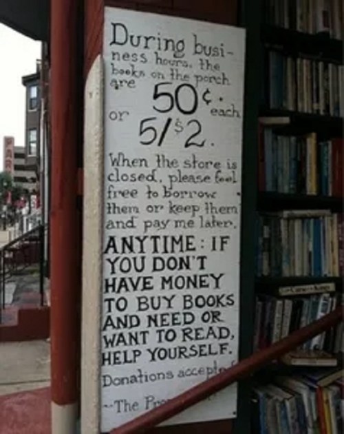 Sign on a bookstore porch offering books for sale and encouraging those in need to take them for free.