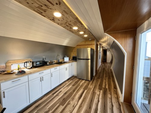 full kitchen with wood floors and steel fridge inside airplane house