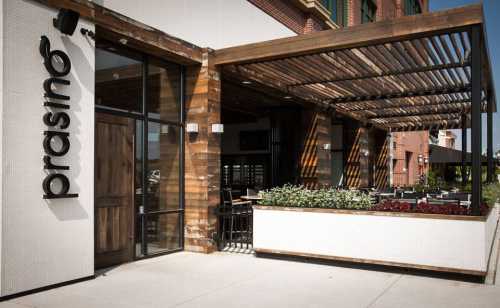 Exterior of Prasino restaurant featuring a wooden awning, outdoor seating, and a modern design.