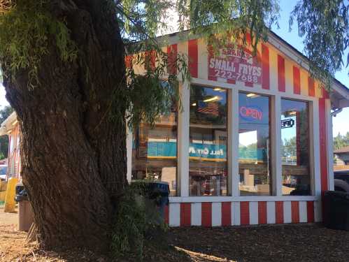 A colorful striped building with an "OPEN" sign, surrounded by trees and outdoor seating.