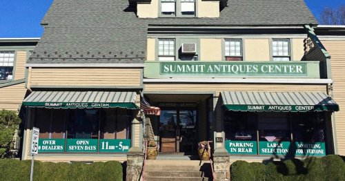 Exterior of Summit Antiques Center, a large building with green signage, showcasing windows and a welcoming entrance.