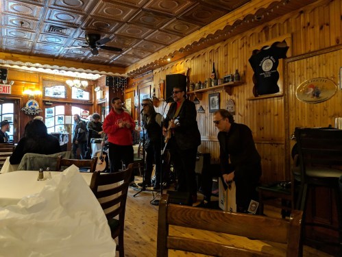A band performs in a cozy wooden venue with patrons enjoying the music and a casual atmosphere.