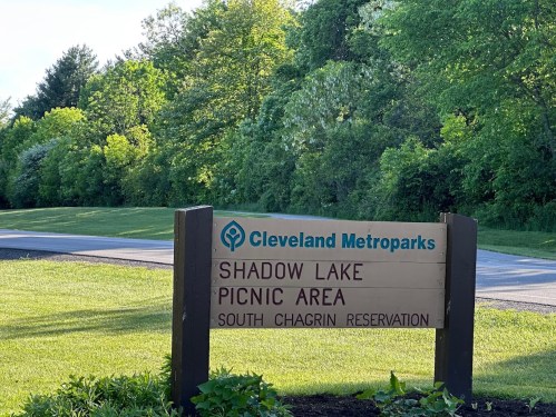 Sign for Shadow Lake Picnic Area at Cleveland Metroparks, surrounded by greenery and trees.