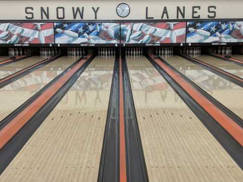 A bowling alley with polished lanes, colorful murals, and a clock on the wall, featuring the name "Snowy Lanes."