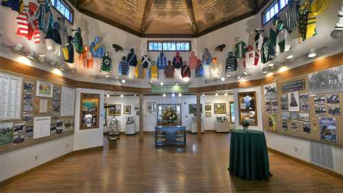 Interior of a museum featuring colorful jockey silks hanging from the ceiling, with displays and photographs on the walls.