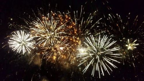 Colorful fireworks explode in the night sky, creating a vibrant display of light and sparks.