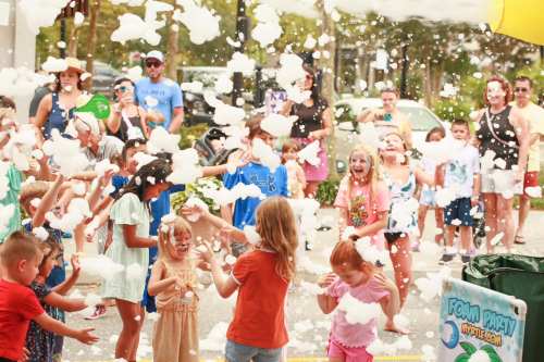 A lively foam party with children and adults enjoying bubbles and foam, laughing and playing in a festive atmosphere.