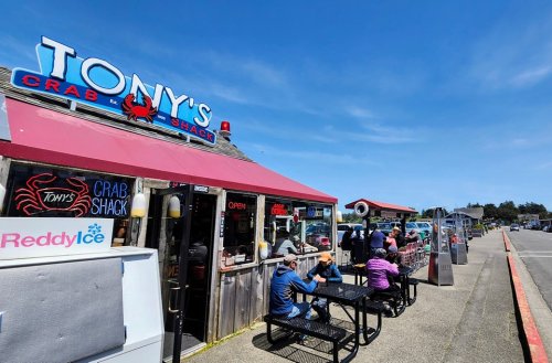 Exterior of Tony's Crab Shack with diners at outdoor tables and a clear blue sky in the background.