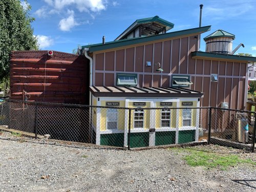 A colorful building with a fenced area, featuring windows and a water tower on the roof, set against a blue sky.