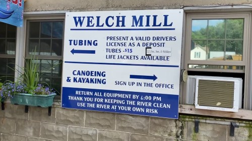 Sign at Welch Mill detailing tubing, canoeing, and kayaking rentals, with safety and deposit information.