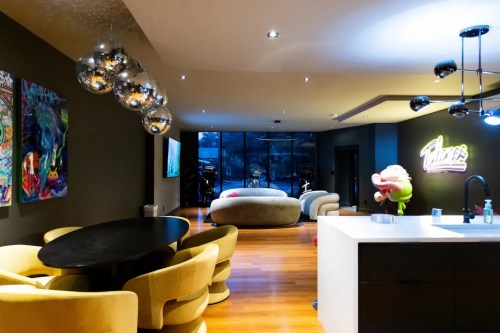 Modern living space featuring a dining area, plush seating, colorful artwork, and stylish lighting fixtures.