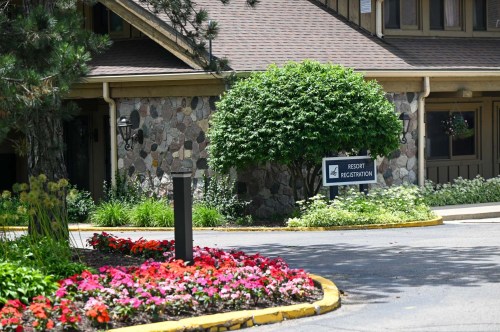 A resort registration area with a stone facade, lush greenery, and colorful flower beds in front.