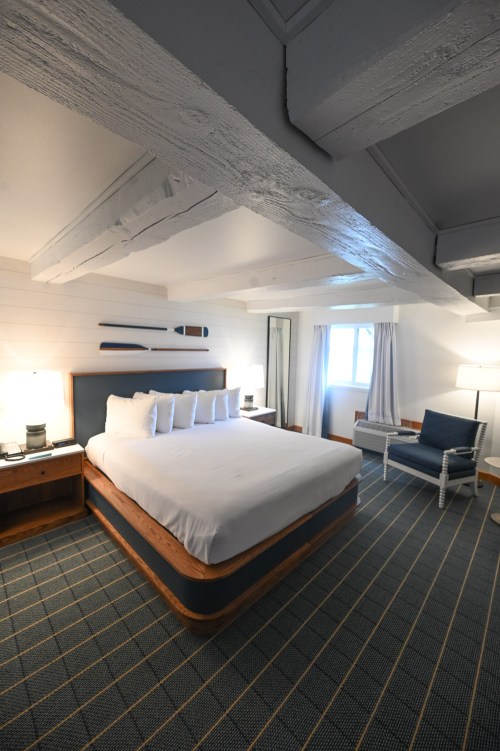 Cozy hotel room featuring a large bed, wooden accents, and a seating area with natural light from a window.