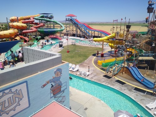 A vibrant water park featuring colorful slides, a lazy river, and sunbathers enjoying a sunny day.