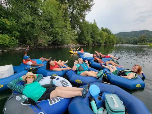 A group of people relaxing on inflatable tubes in a river, surrounded by trees and enjoying a sunny day.