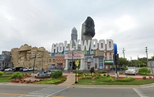 A large "HOLLYWOOD" sign in front of a themed building featuring sculptures and attractions.