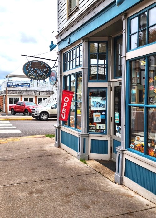 A corner shop with large windows displaying items, featuring an "OPEN" sign and a view of a street in the background.
