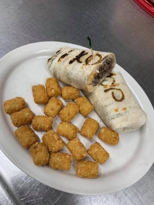 A plate with two burritos and a serving of golden tater tots on the side.