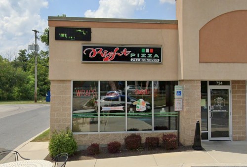 Exterior of Right Pizza restaurant with a sign, large windows, and a menu display. Clear blue sky in the background.