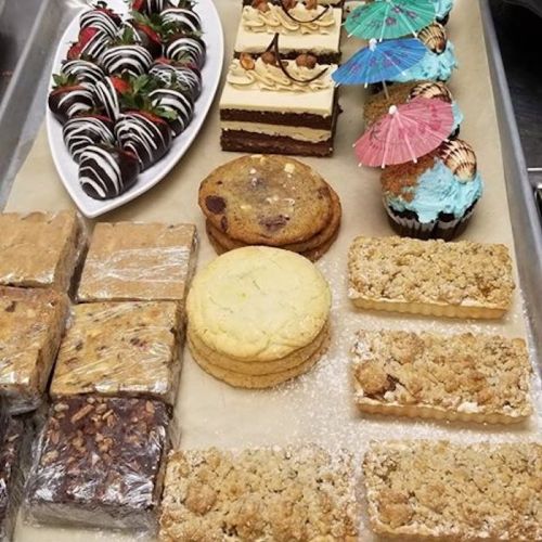 A variety of desserts including chocolate-covered strawberries, cakes, cookies, and bars, arranged on a tray.