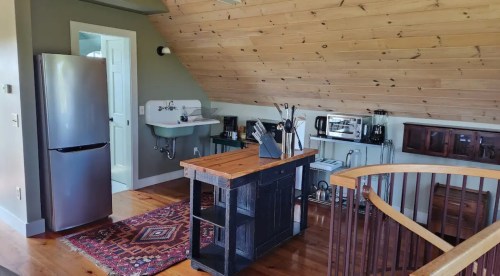 Cozy kitchen with wooden ceiling, stainless steel appliances, and a central island on a rustic floor.