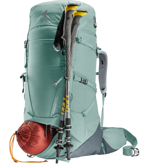 A teal hiking backpack with trekking poles attached and a red sleeping bag peeking out from the side pocket.