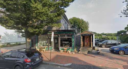 A street view of a café named "Chaval" with outdoor seating and a free pantry nearby, surrounded by trees and parked cars.