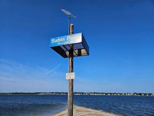 Sign for Sabin Point in Riverside, RI, with a blue sky and water in the background.