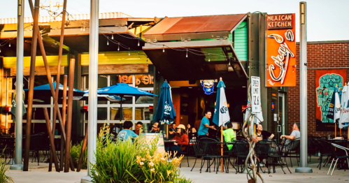 Outdoor dining area of a Mexican restaurant with colorful umbrellas and patrons enjoying their meals.