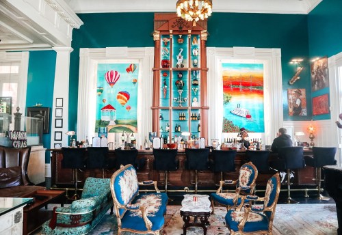 A vibrant bar area with colorful artwork, elegant seating, and a stylish decor featuring hot air balloons and landscapes.