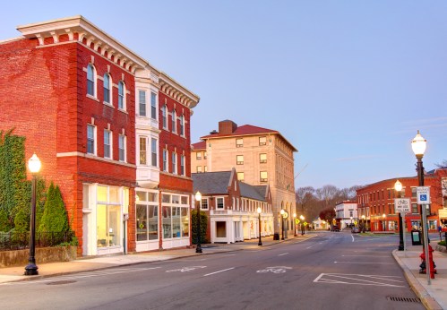 A quiet street scene featuring historic brick buildings and lampposts at dusk.