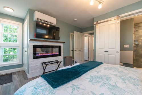 Cozy bedroom with a fireplace, TV, and sliding door, featuring light blue walls and a floral bedspread.