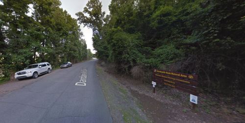 A winding road leads into a wooded area, with a sign for Dardanelle Rock Natural Area visible on the right.