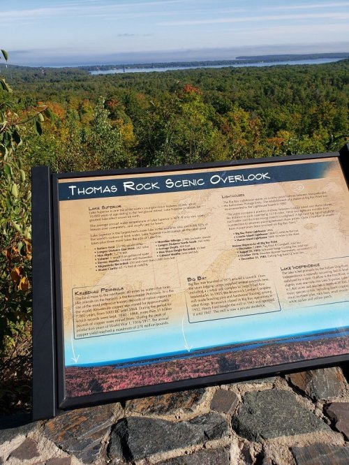 Sign at Thomas Rock Scenic Overlook with a view of a lake and forested landscape in the background.