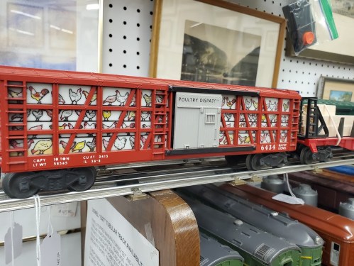 A model train car painted red, featuring a poultry theme with chickens illustrated on the sides.