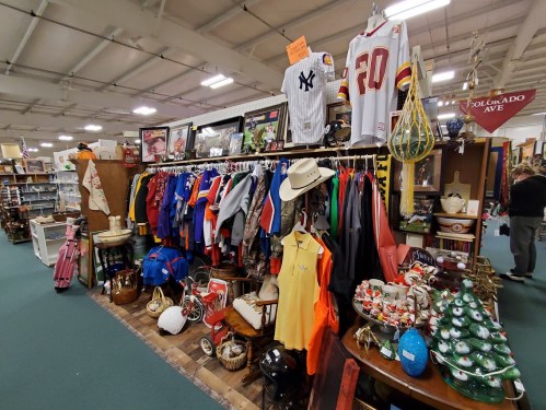 A vibrant display of vintage clothing, sports jerseys, and various collectibles in a bustling thrift store.