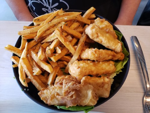 A bowl filled with golden fries and crispy fried fish, served on a bed of lettuce.