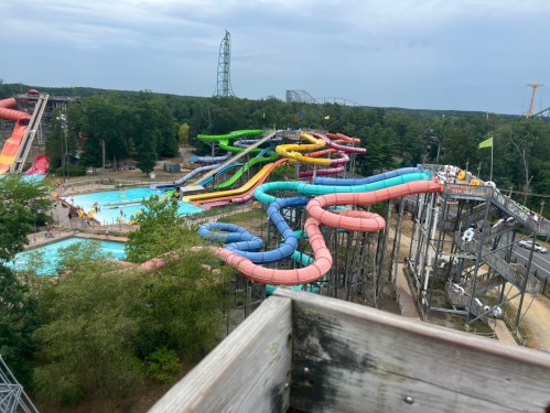 Aerial view of a water park featuring colorful slides, a pool, and lush greenery in the background.
