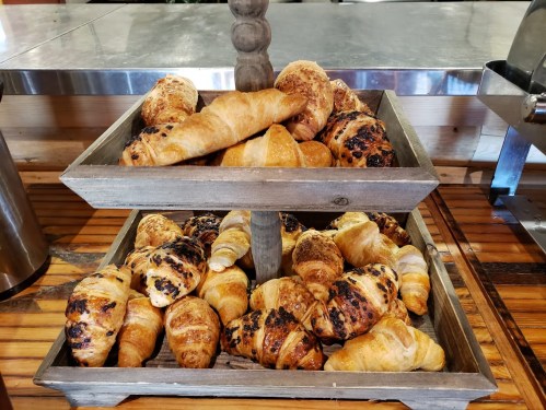 A wooden display stand filled with various freshly baked croissants and pastries.