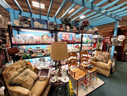 A cozy antique shop display featuring vintage furniture, collectibles, and decorative items on shelves.