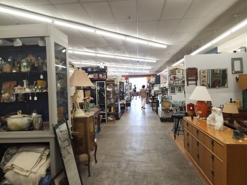 A spacious antique store aisle lined with various vintage items, furniture, and decorative pieces.