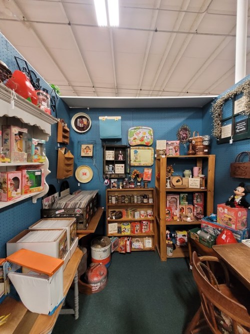 A cozy vintage shop corner filled with shelves of toys, collectibles, and nostalgic items against a blue wall.