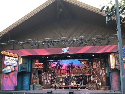 A stage set with a tropical backdrop, guitars, and various music-themed decorations, ready for a performance.